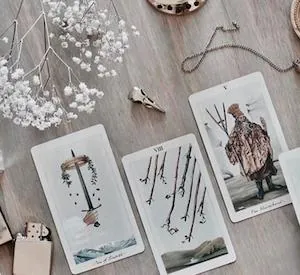 Cartas de tarot con flores secas sobre una mesa de madera clara