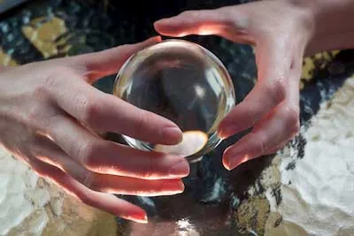 Manos rodeando una bola de cristal durante una sesión de videncia