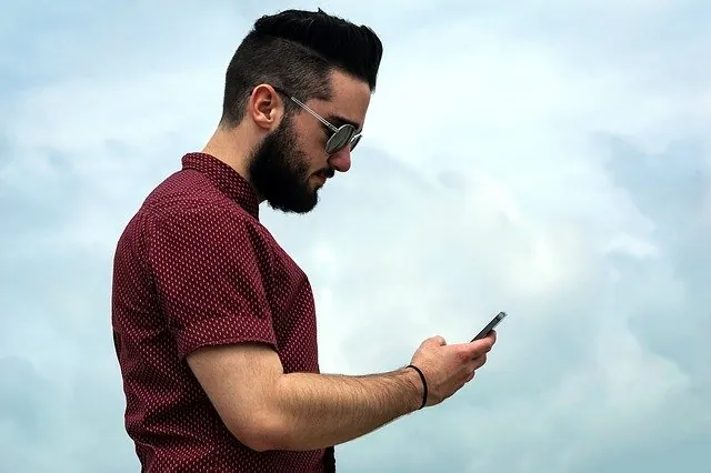Hombre consultando su móvil para pagar el tarot con PayPal